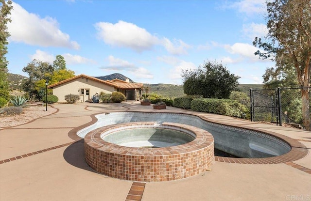 view of pool featuring a gate and a pool with connected hot tub