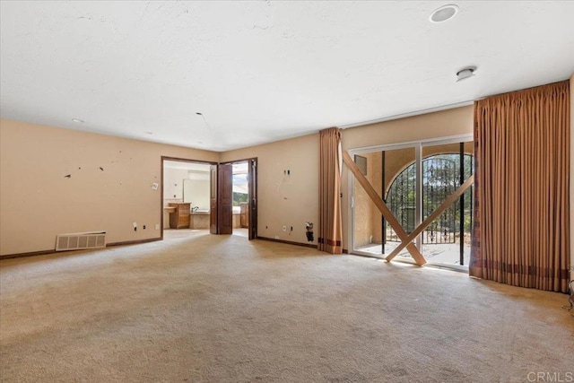 spare room featuring light carpet, baseboards, visible vents, and a wealth of natural light