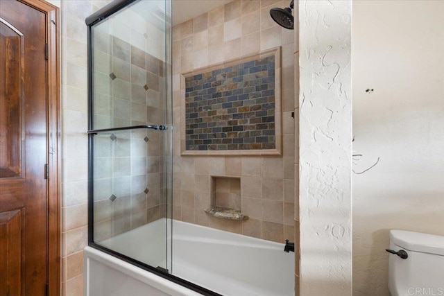 full bathroom with toilet and bath / shower combo with glass door