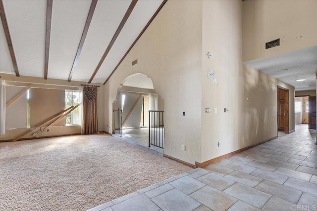 spare room featuring high vaulted ceiling, arched walkways, beam ceiling, and carpet flooring