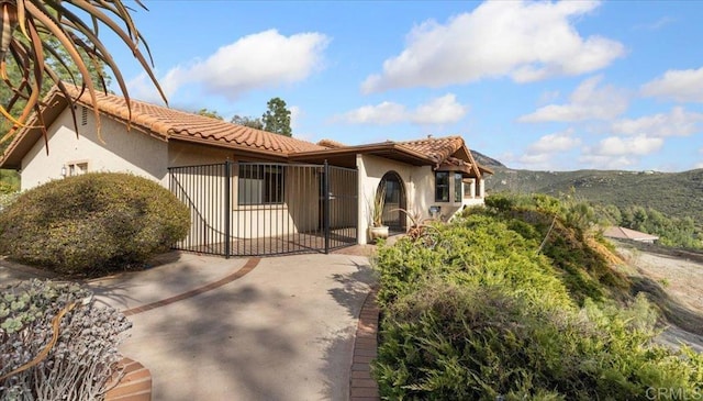 view of front facade with a gate, a tiled roof, and stucco siding