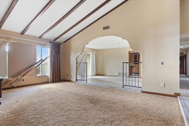 carpeted empty room with arched walkways, visible vents, high vaulted ceiling, beamed ceiling, and baseboards