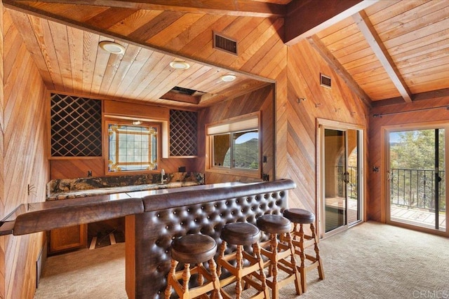 bar featuring wooden walls, visible vents, lofted ceiling with beams, wood ceiling, and wet bar