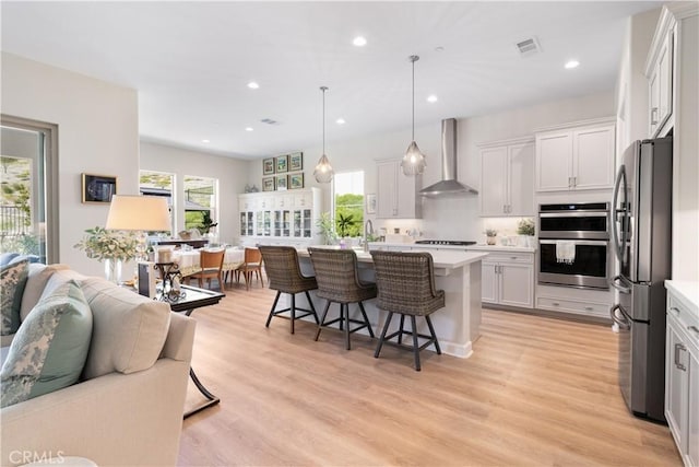24674 Crestley Dr, Corona, CA 92883 - kitchen with wall chimney exhaust hood, stainless steel appliances, light countertops, a breakfast bar area, and recessed lighting