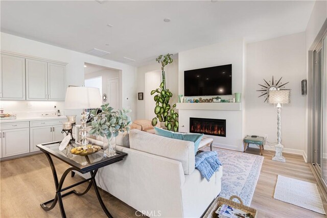 24674 Crestley Dr, Corona, CA 92883 - living area with light wood finished floors, a lit fireplace, and baseboards