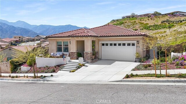 24674 Crestley Dr, Corona, CA 92883 - mediterranean / spanish-style home with stucco siding, an attached garage, driveway, a mountain view, and a tiled roof