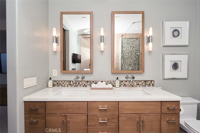 full bathroom with toilet, double vanity, backsplash, and a sink