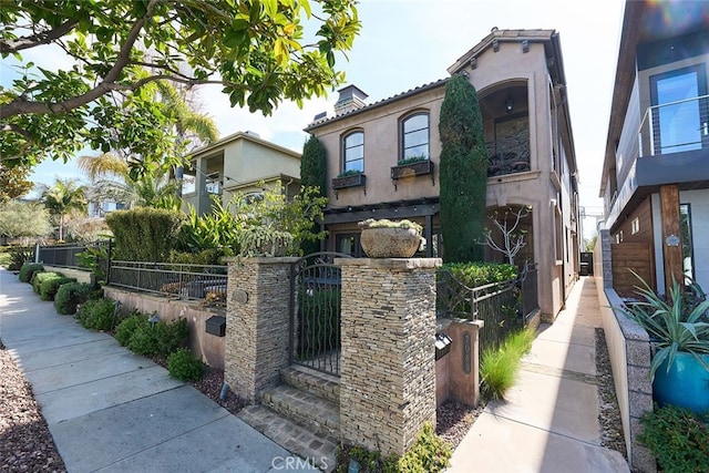 view of side of home featuring a fenced front yard, a gate, and stucco siding