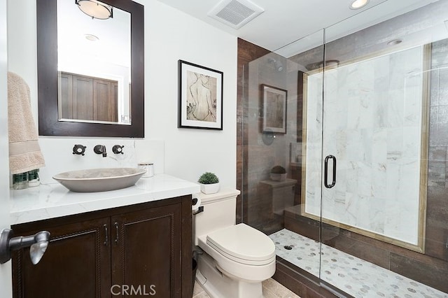 bathroom with a stall shower, visible vents, vanity, and toilet