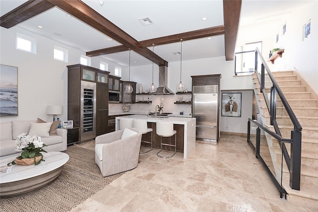 kitchen with stainless steel appliances, wall chimney range hood, beamed ceiling, and visible vents