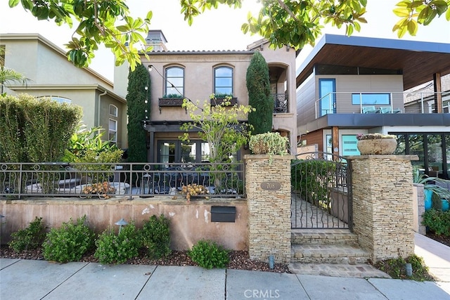 view of front of property featuring a fenced front yard, a gate, a tiled roof, and stucco siding