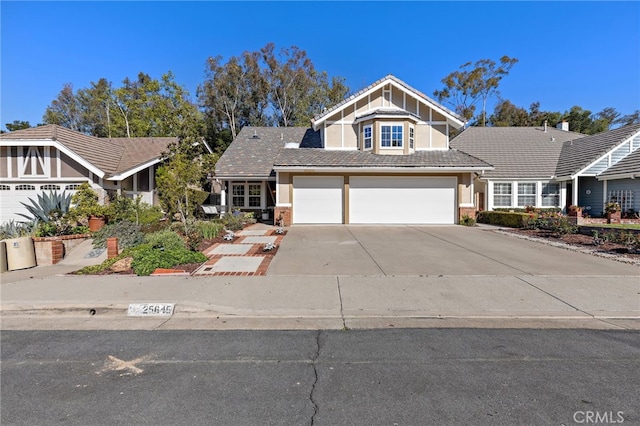 view of front of property with a tile roof, an attached garage, driveway, and stucco siding