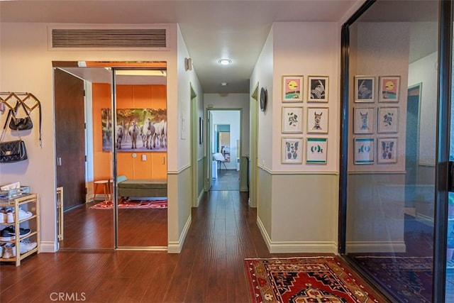 corridor featuring dark wood-style floors, visible vents, and baseboards