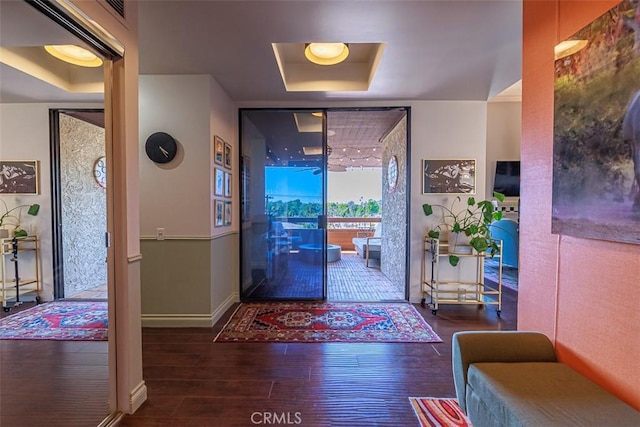 foyer entrance featuring visible vents, a raised ceiling, baseboards, and wood finished floors