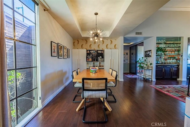 dining area featuring dark wood-style floors, visible vents, baseboards, an inviting chandelier, and a tray ceiling