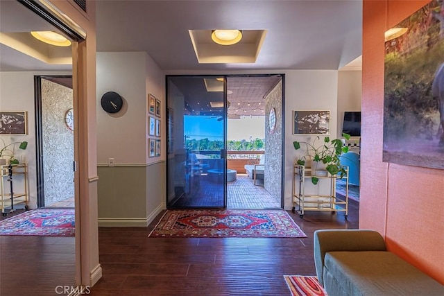 entryway with visible vents, a raised ceiling, baseboards, and wood finished floors