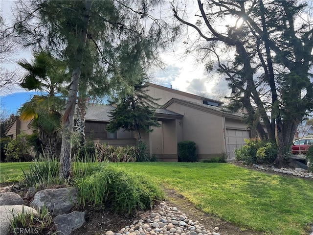 view of home's exterior featuring a garage, a yard, and stucco siding