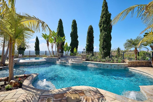 view of pool featuring a pool with connected hot tub and fence