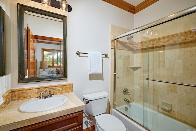 full bath featuring vanity, toilet, combined bath / shower with glass door, and ornamental molding