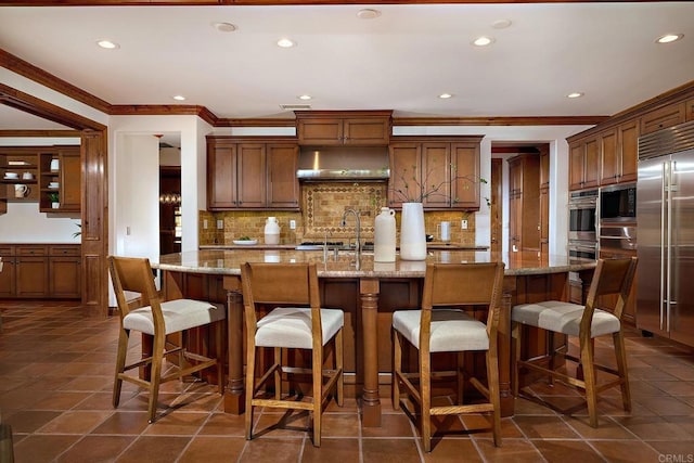 kitchen with stainless steel built in refrigerator, decorative backsplash, crown molding, and a sink