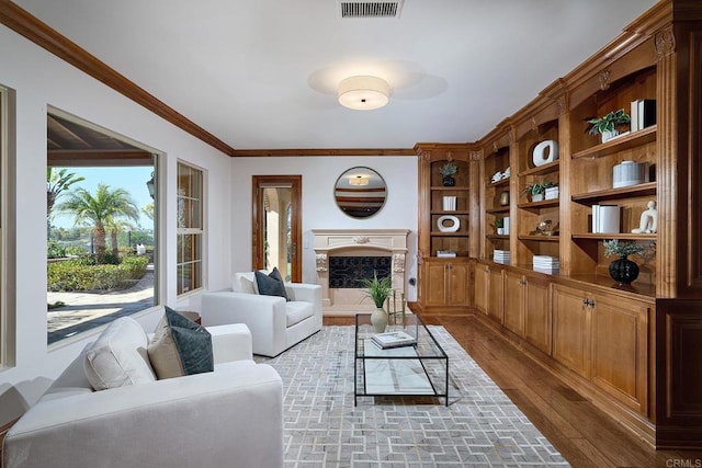 living area featuring a premium fireplace, wood finished floors, visible vents, and ornamental molding