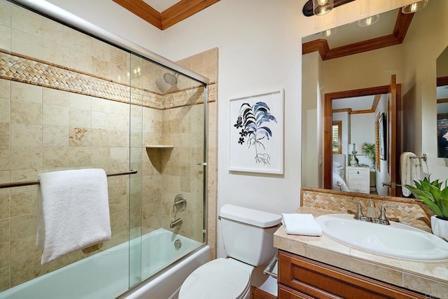 full bathroom with bath / shower combo with glass door, toilet, vanity, and ornamental molding