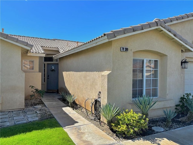 doorway to property featuring a tiled roof and stucco siding