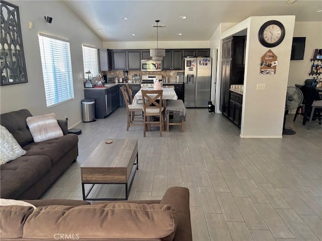 living area with lofted ceiling, recessed lighting, baseboards, and light wood-style floors