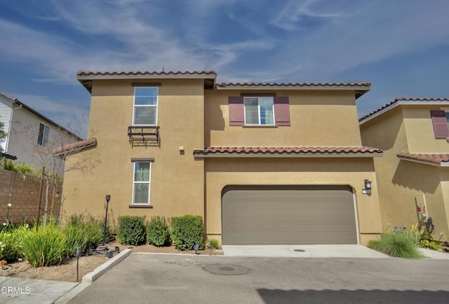 mediterranean / spanish house featuring concrete driveway, an attached garage, fence, and stucco siding