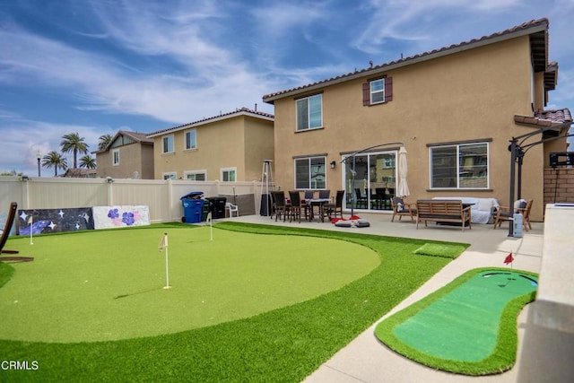 rear view of property featuring stucco siding, a tile roof, fence, and a patio