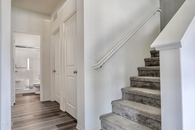 stairs with visible vents and wood finished floors