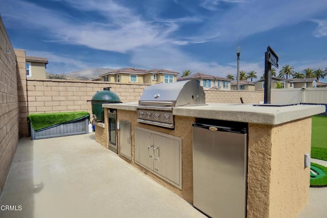 view of patio / terrace featuring an outdoor kitchen, a fenced backyard, a residential view, and a grill