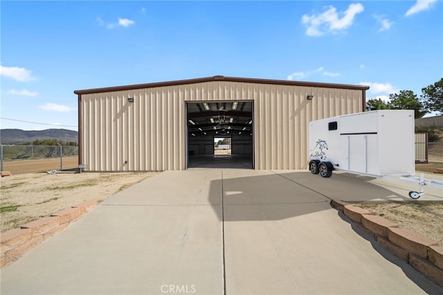 view of pole building featuring concrete driveway and fence