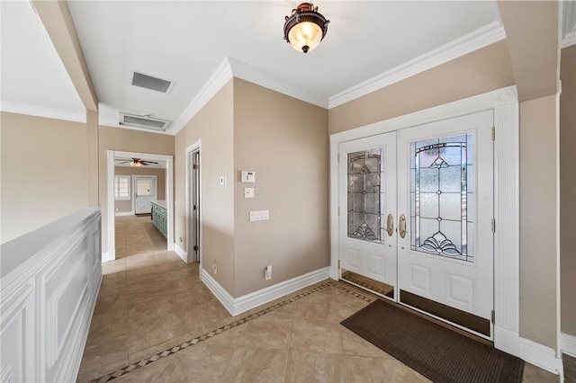 foyer with light tile patterned floors, visible vents, baseboards, ornamental molding, and french doors