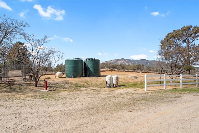 view of yard with a rural view, a mountain view, and fence