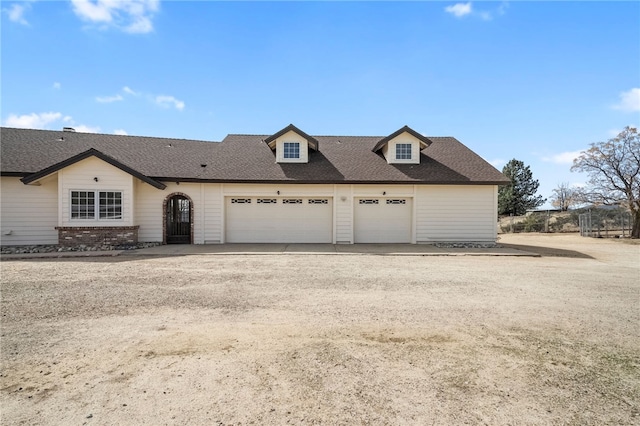 view of front of home with driveway, roof with shingles, a garage, and brick siding