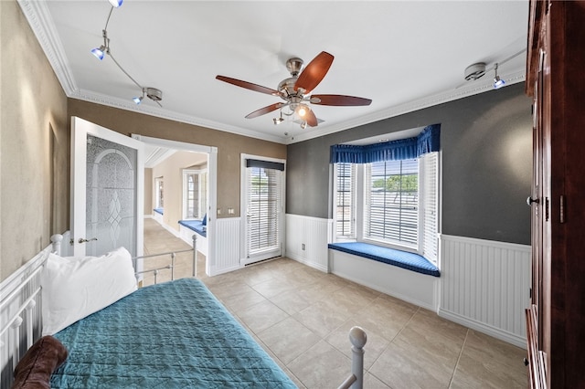 bedroom with a wainscoted wall, ornamental molding, and track lighting