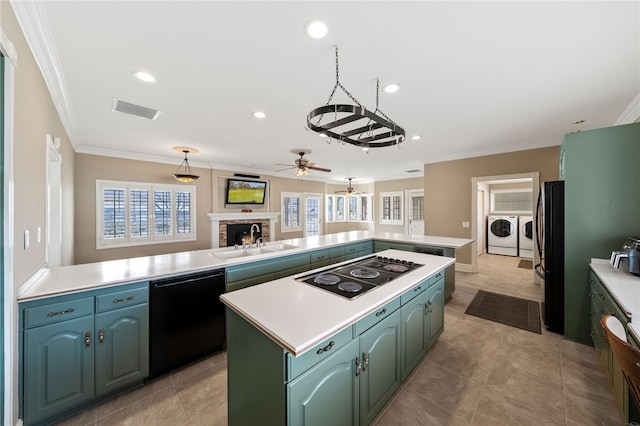 kitchen with washing machine and clothes dryer, light countertops, a kitchen island, a sink, and black appliances