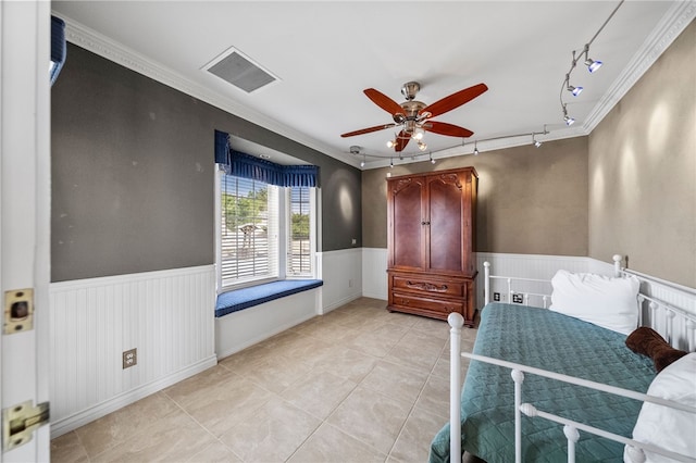 bedroom with a wainscoted wall, visible vents, and crown molding