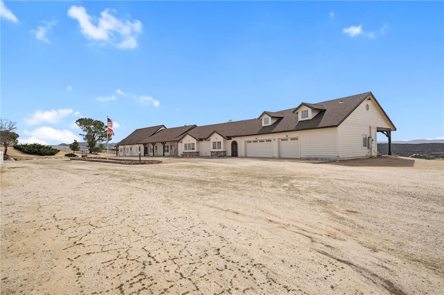 view of front of property with an attached garage and dirt driveway