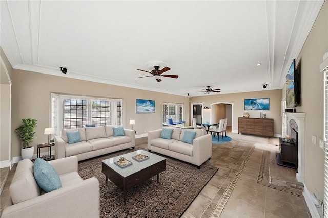 living area featuring ornamental molding, a fireplace, a ceiling fan, and baseboards