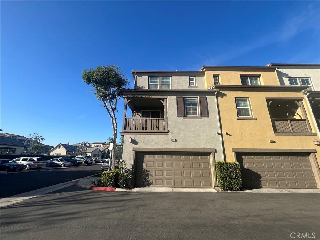 multi unit property featuring an attached garage, a balcony, and stucco siding