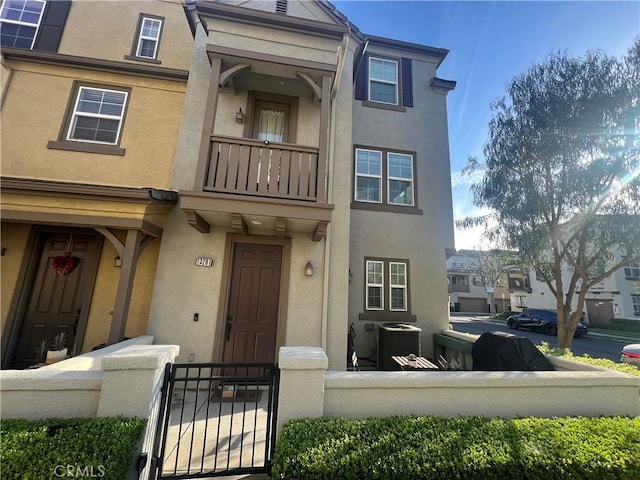 view of property featuring central AC, a balcony, and stucco siding