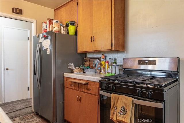 kitchen with light countertops, appliances with stainless steel finishes, brown cabinetry, and backsplash