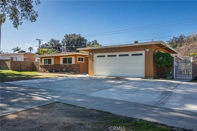 ranch-style home with concrete driveway, fence, an attached garage, and stucco siding