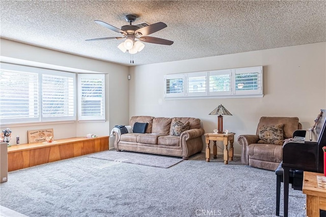 carpeted living area with ceiling fan and a textured ceiling