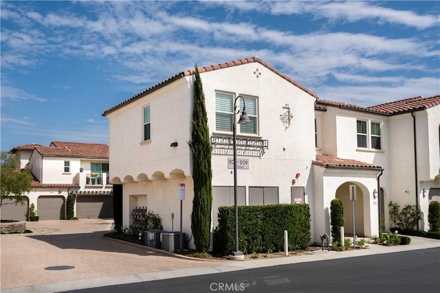 mediterranean / spanish-style house featuring a tile roof, concrete driveway, stucco siding, and an attached garage
