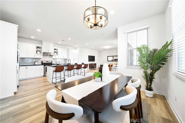 dining area featuring a chandelier, light wood finished floors, recessed lighting, and baseboards