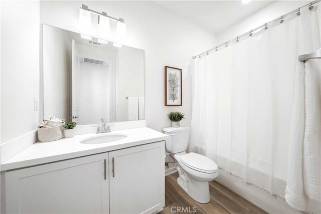 bathroom featuring wood finished floors, toilet, vanity, and shower / tub combo