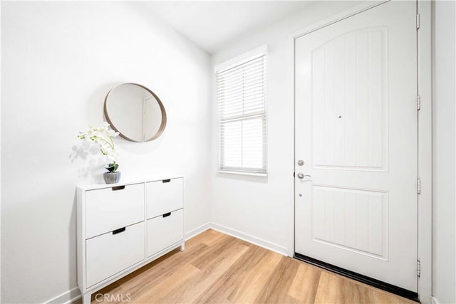 doorway to outside with light wood finished floors and baseboards